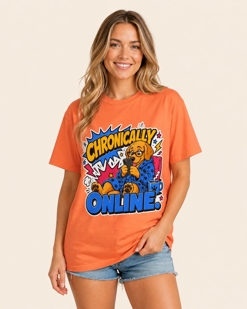 A woman wearing a bright orange graphic t-shirt with a cartoon dog design that reads 'Chronically Online' in comic-style text, paired with denim shorts, against a solid beige background.